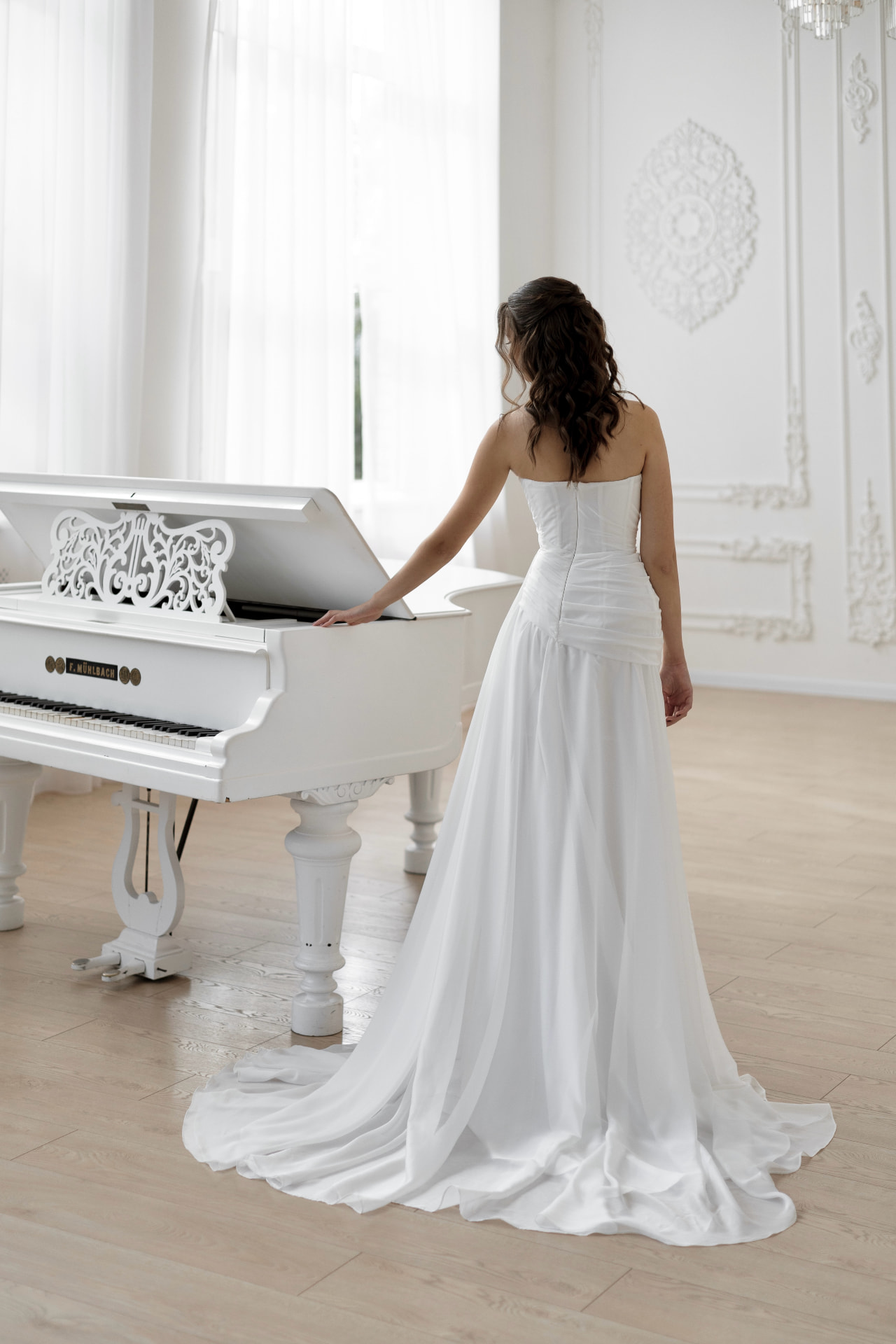 Harmonia — back view beside a grand piano with sweeping train