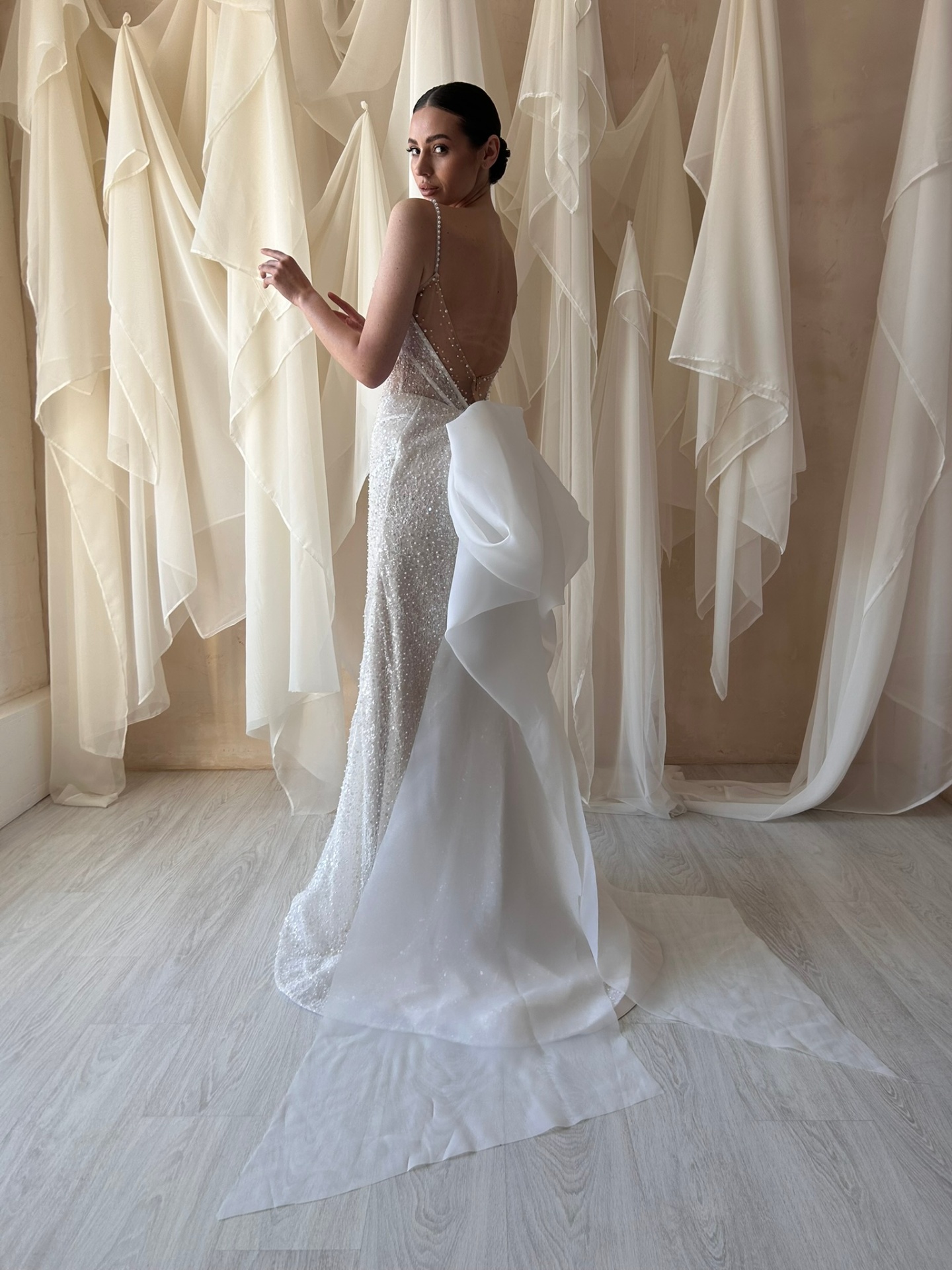 Michele — back view with sheer open back, pearl-strap detail and dramatic voluminous bow flowing into the train