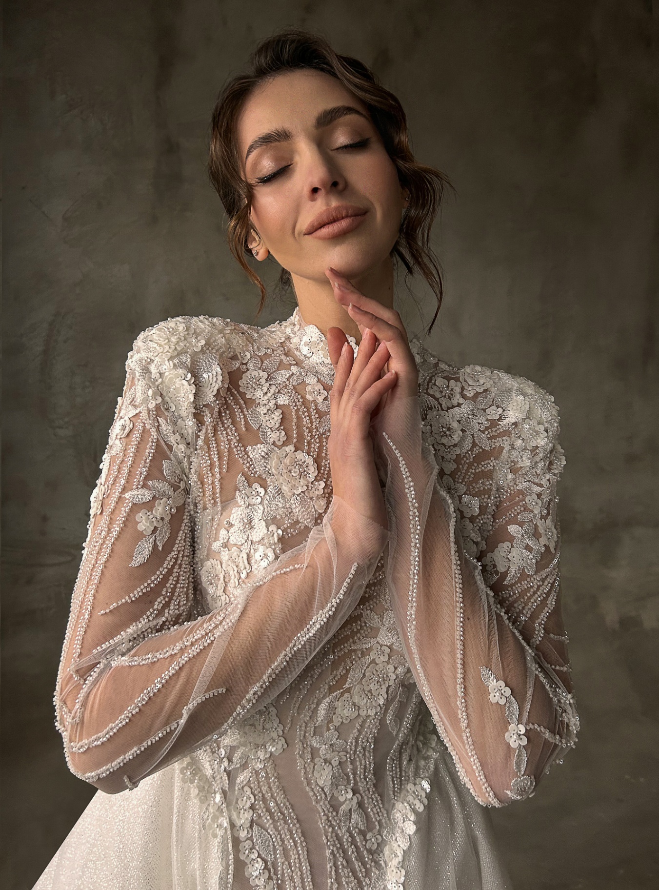 Ornella — close-up portrait highlighting the intricate floral appliqués, sheer high-neck bodice and embellished long sleeves