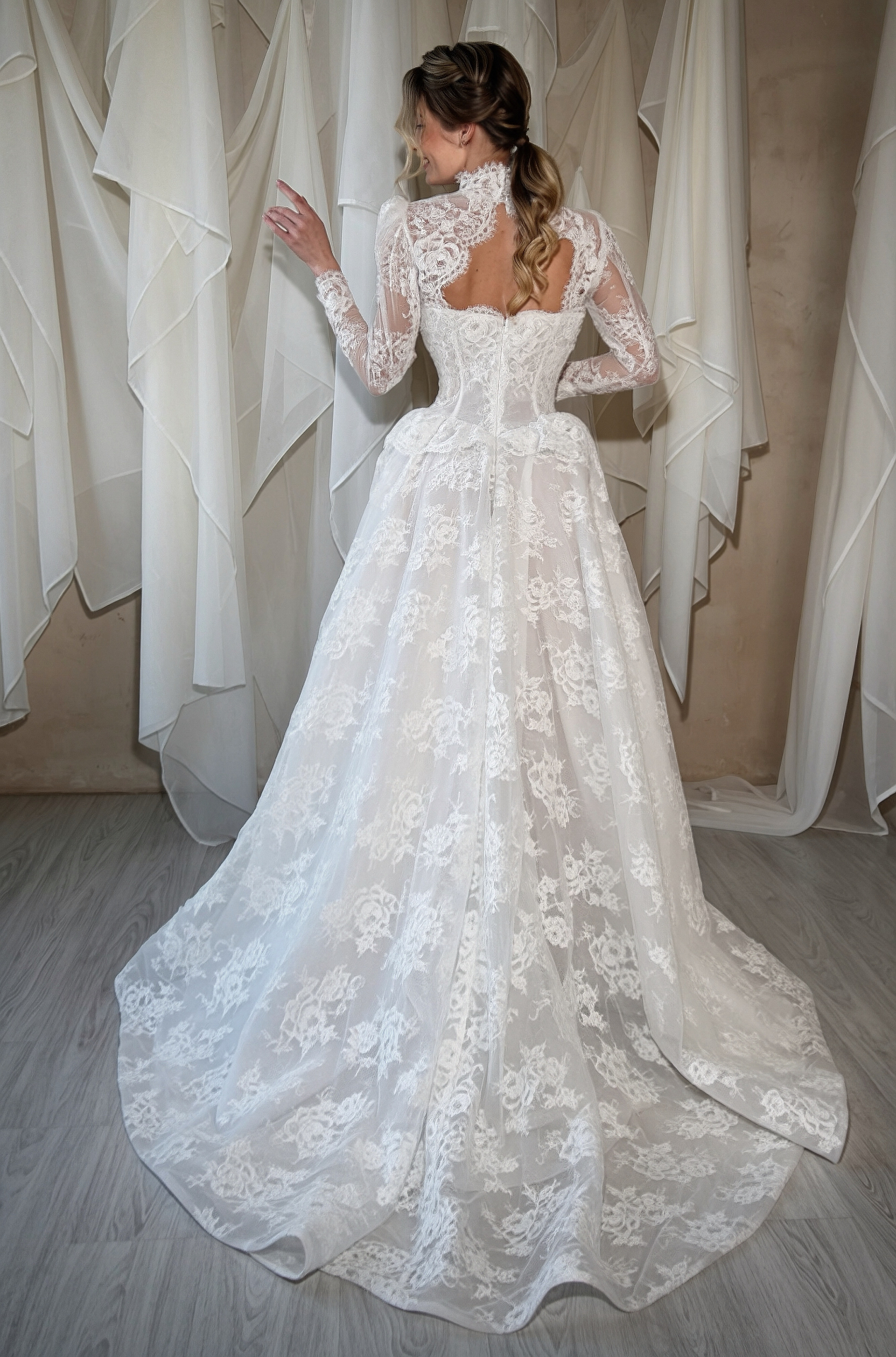 Monica — back view highlighting the open back cutout, long lace sleeves and sweeping lace train