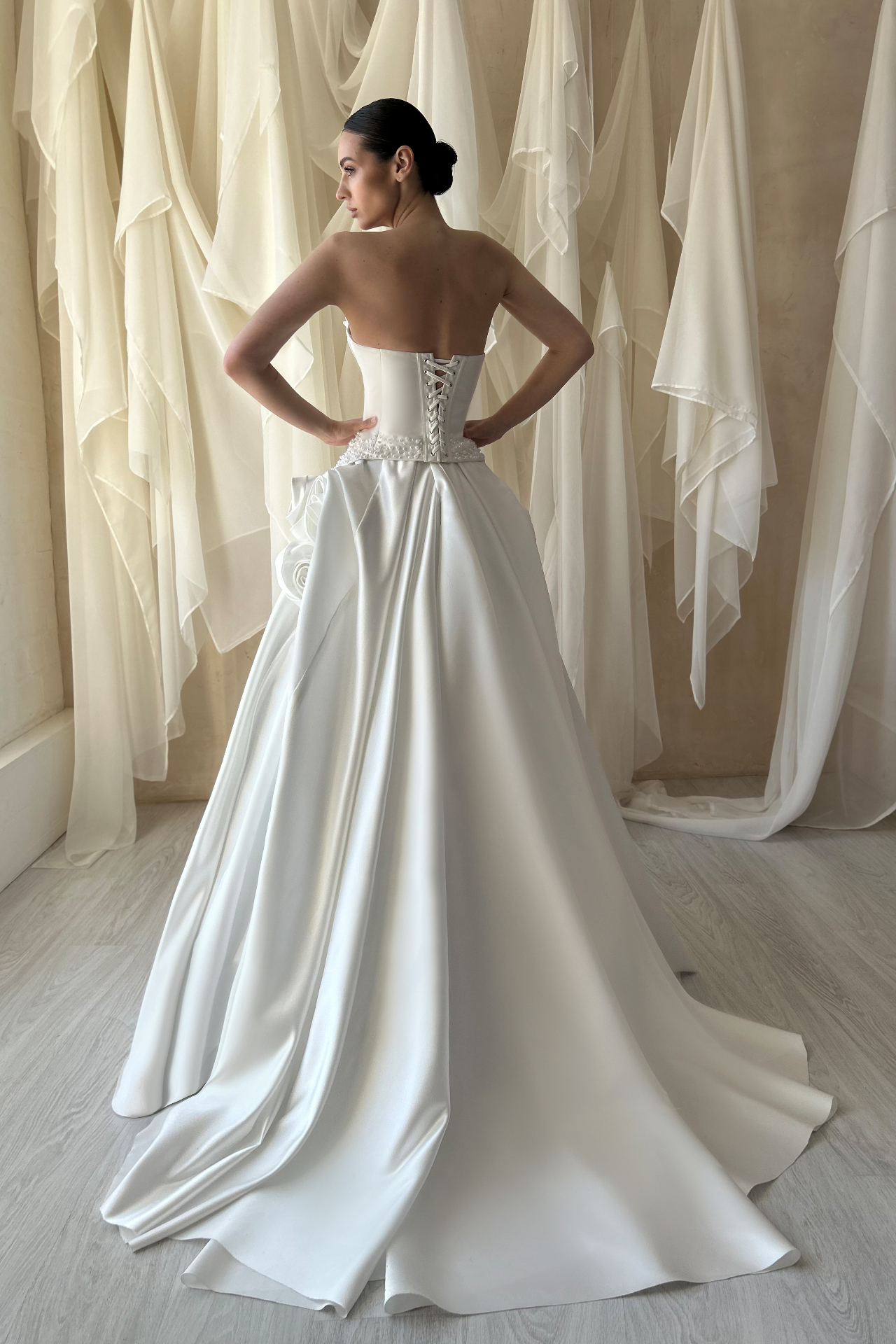 Madeline — back view showing corset lacing and dramatic satin train with rosette detail