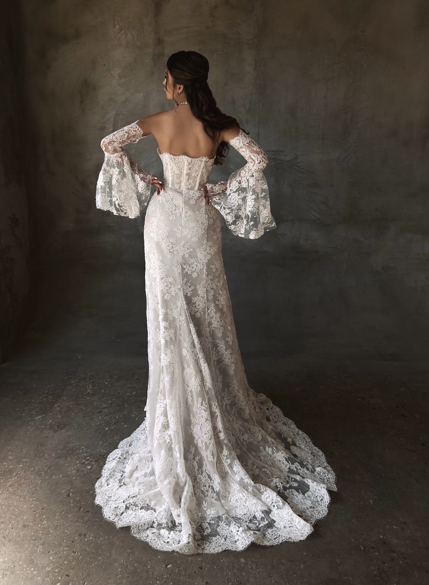Patricia — back view showcasing the strapless lace corset bodice, flared bell sleeves and sweeping scalloped lace train
