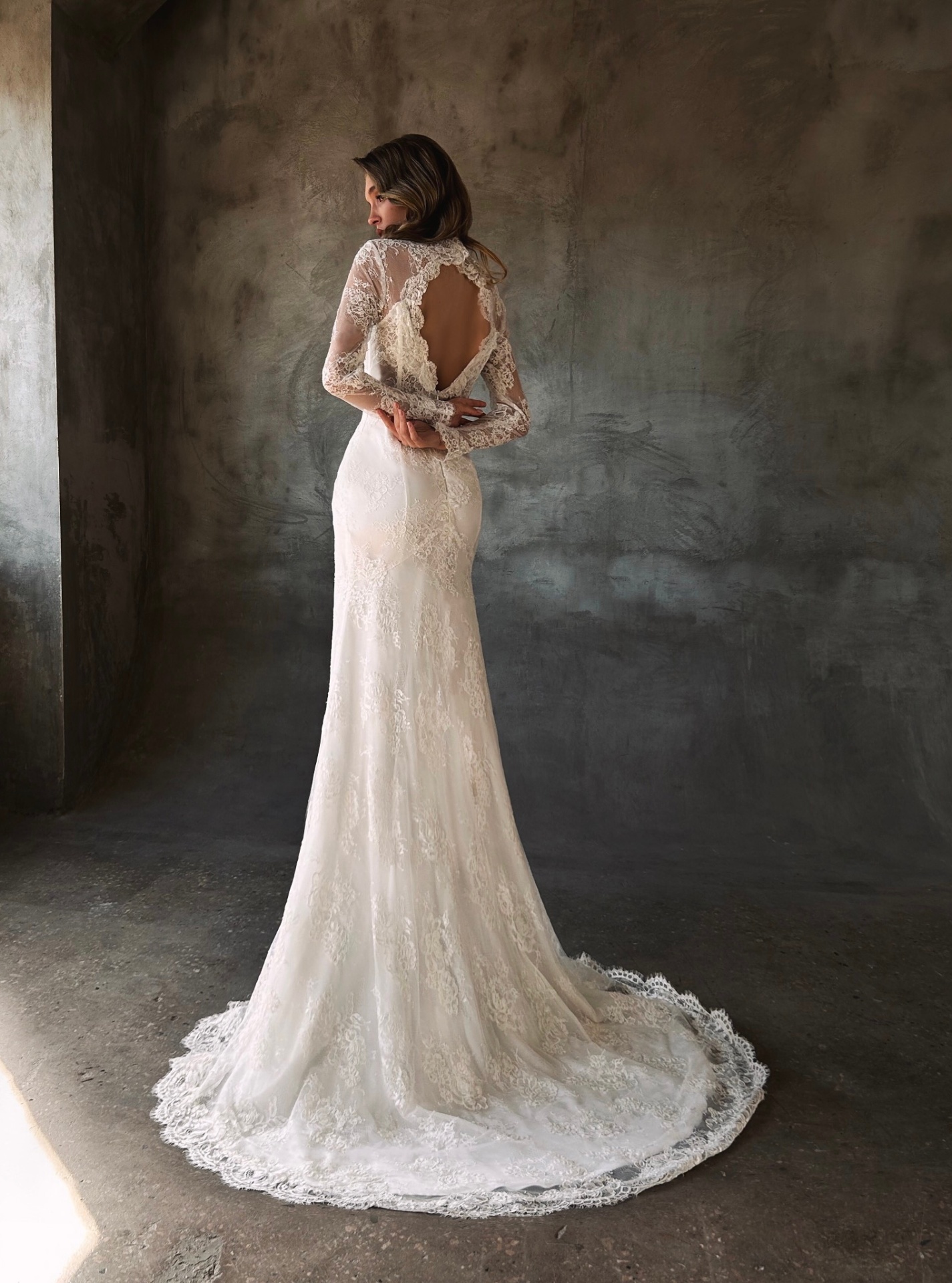 Madlen — back view of the fitted lace gown with dramatic open back and trailing lace hem